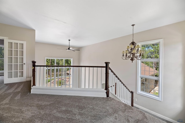 empty room with plenty of natural light, ceiling fan with notable chandelier, and carpet flooring