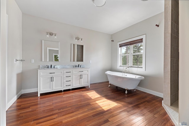 bathroom with wood-type flooring, vanity with extensive cabinet space, double sink, and a bathtub