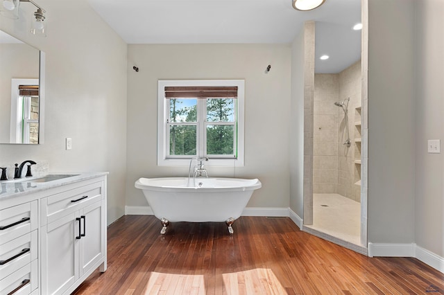 bathroom with a tile shower, wood-type flooring, and vanity