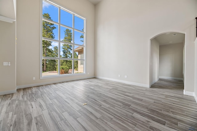 empty room with a high ceiling and light hardwood / wood-style floors