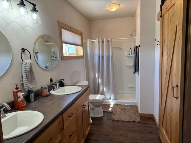 bathroom featuring oversized vanity, toilet, wood-type flooring, walk in shower, and double sink