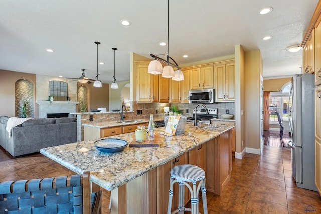 kitchen featuring a center island, hanging light fixtures, appliances with stainless steel finishes, kitchen peninsula, and backsplash