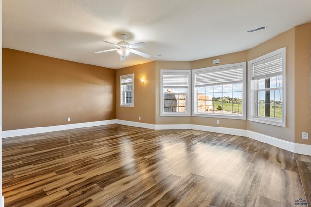 empty room featuring dark wood-type flooring and ceiling fan