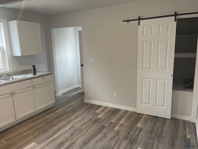 kitchen with dark hardwood / wood-style floors, a barn door, white cabinetry, and sink