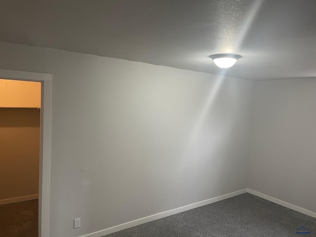 spare room with a textured ceiling and dark carpet