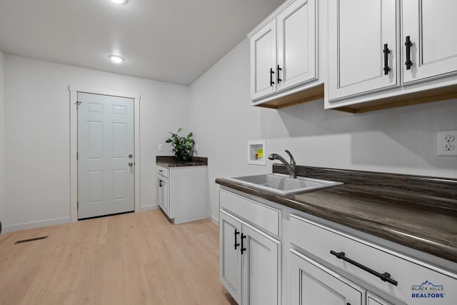 kitchen with light hardwood / wood-style floors, white cabinetry, and sink