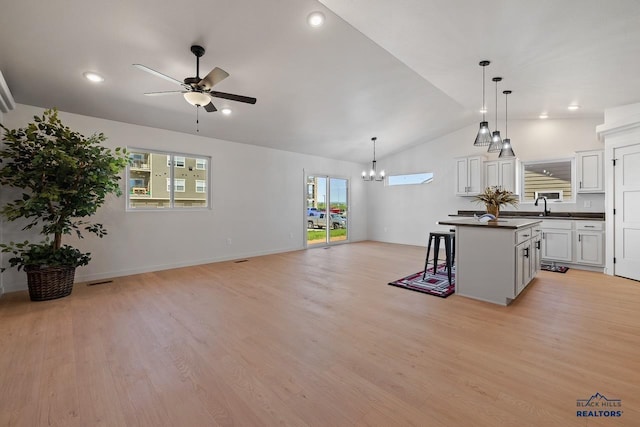 kitchen featuring white cabinetry, a breakfast bar, hanging light fixtures, a kitchen island, and sink