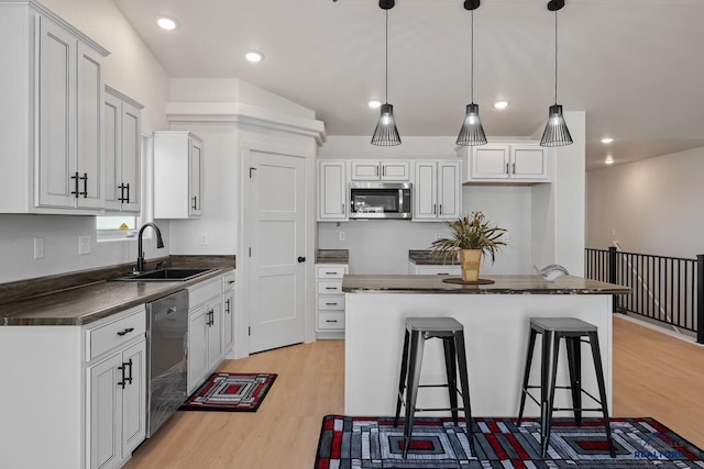 kitchen with appliances with stainless steel finishes, sink, a kitchen bar, and a center island