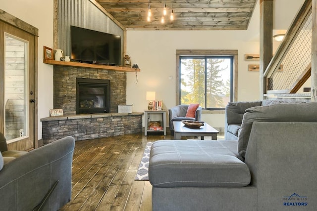 living room featuring hardwood / wood-style floors, wooden ceiling, a stone fireplace, and vaulted ceiling