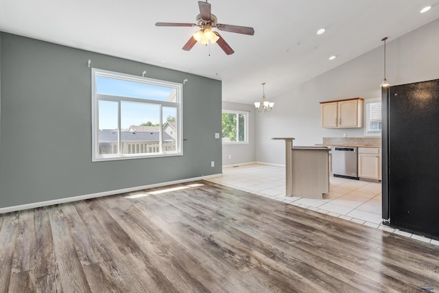 unfurnished living room with ceiling fan with notable chandelier, light hardwood / wood-style floors, and vaulted ceiling