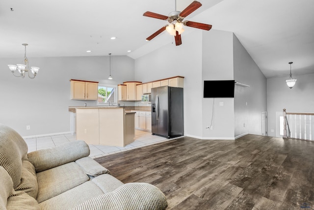 living room featuring ceiling fan with notable chandelier, light hardwood / wood-style floors, and high vaulted ceiling