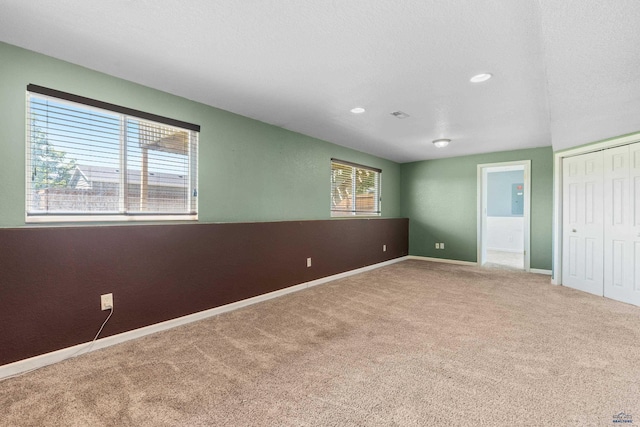 unfurnished bedroom with carpet flooring, multiple windows, a closet, and a textured ceiling