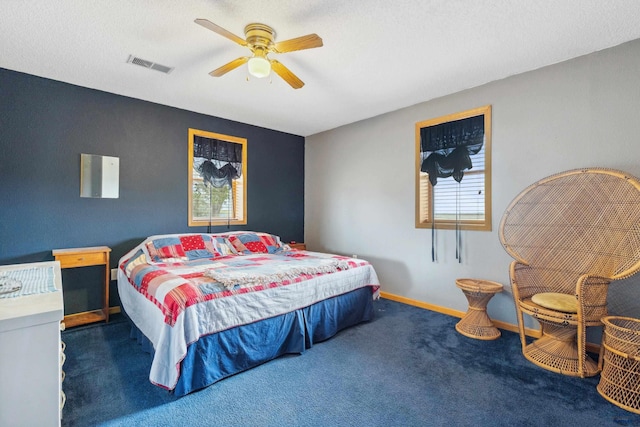 bedroom featuring ceiling fan, a textured ceiling, and dark colored carpet