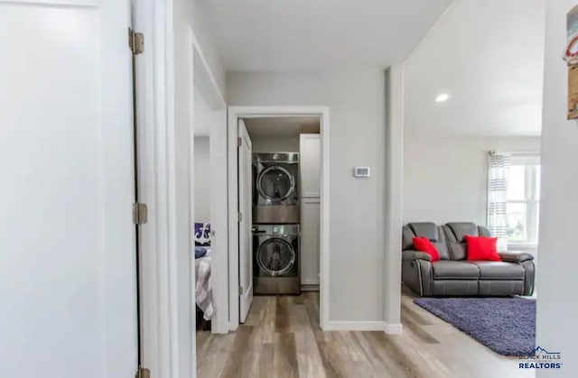 hallway with stacked washing maching and dryer and light wood-type flooring