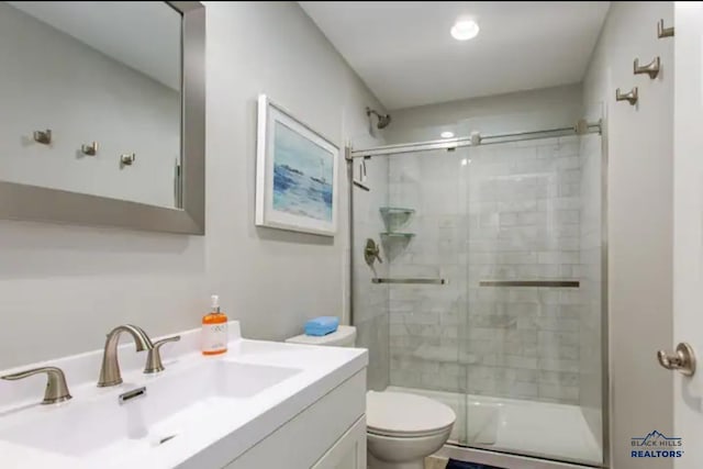 bathroom with a shower with door, vanity, and toilet