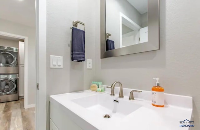 bathroom featuring vanity, wood-type flooring, and stacked washing maching and dryer