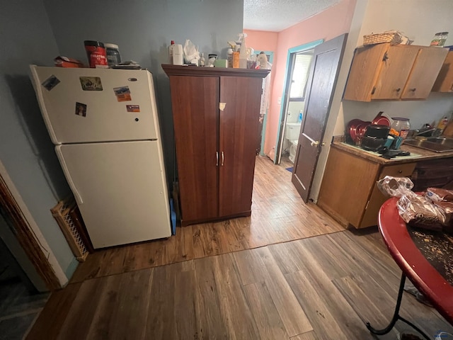 kitchen with white fridge, light hardwood / wood-style floors, sink, and a textured ceiling