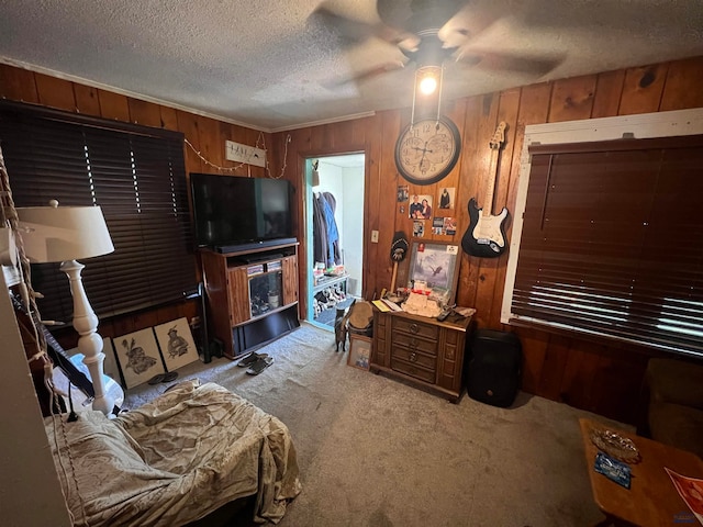 living room featuring wooden walls, a textured ceiling, ceiling fan, and carpet flooring