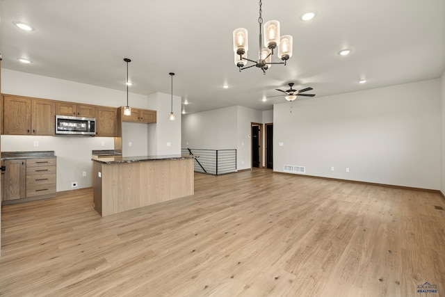 kitchen with ceiling fan with notable chandelier, a kitchen island, hanging light fixtures, and light wood-type flooring