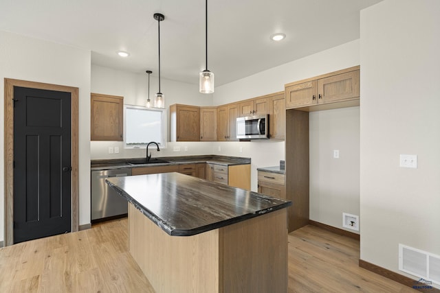 kitchen featuring decorative light fixtures, sink, a kitchen island, light hardwood / wood-style floors, and appliances with stainless steel finishes