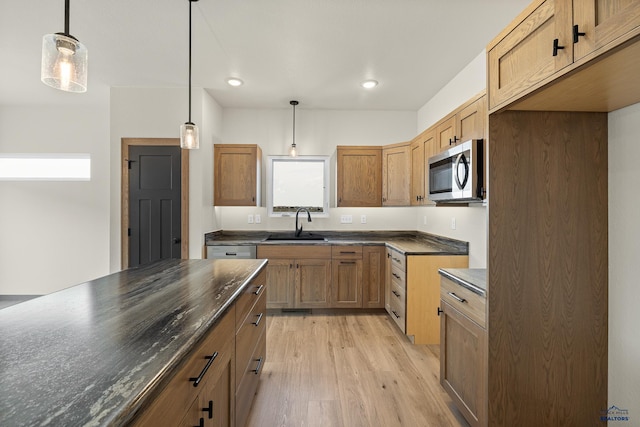 kitchen with sink, appliances with stainless steel finishes, pendant lighting, and light wood-type flooring