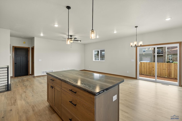 kitchen with a center island, light hardwood / wood-style floors, ceiling fan with notable chandelier, and hanging light fixtures