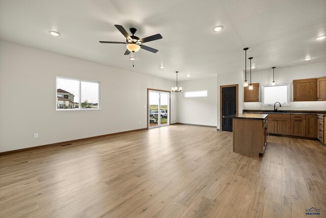 kitchen with sink, decorative light fixtures, ceiling fan with notable chandelier, a center island, and wood-type flooring