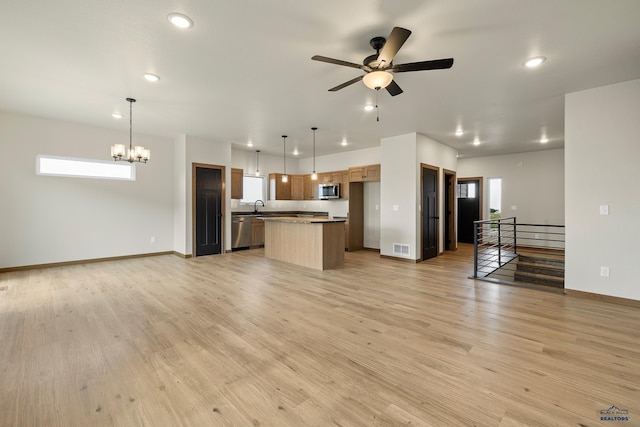 unfurnished living room featuring sink, ceiling fan with notable chandelier, and light hardwood / wood-style floors