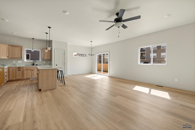 kitchen with light hardwood / wood-style flooring, a breakfast bar, sink, decorative light fixtures, and a kitchen island