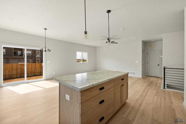 kitchen featuring light hardwood / wood-style floors, a kitchen island, ceiling fan, and decorative light fixtures