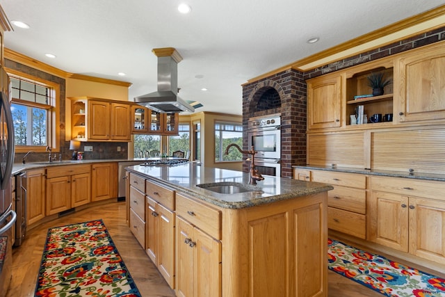 kitchen with sink, island exhaust hood, ornamental molding, a kitchen island with sink, and stainless steel double oven