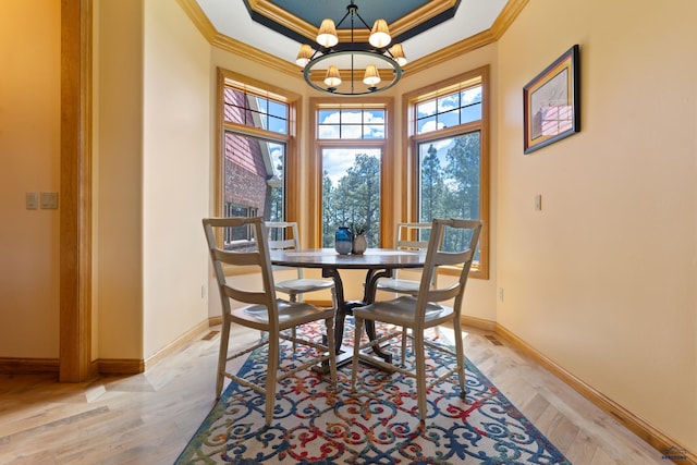 dining area with a notable chandelier, light hardwood / wood-style flooring, ornamental molding, and a raised ceiling