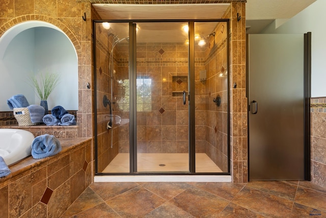 bathroom with tile walls and shower with separate bathtub