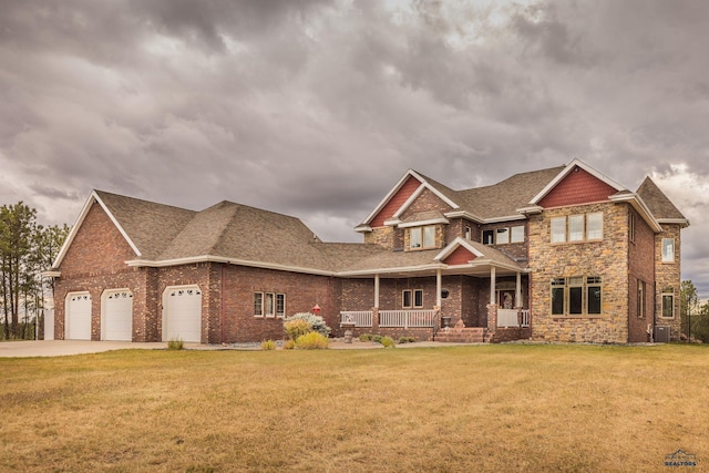 craftsman-style home featuring a porch, a garage, central AC unit, and a front lawn