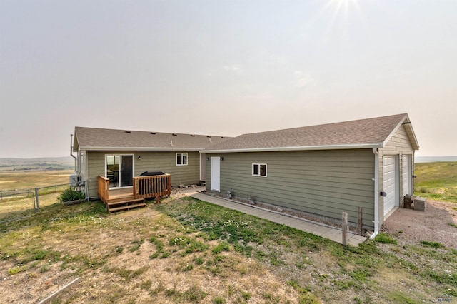 rear view of property featuring a garage and a deck