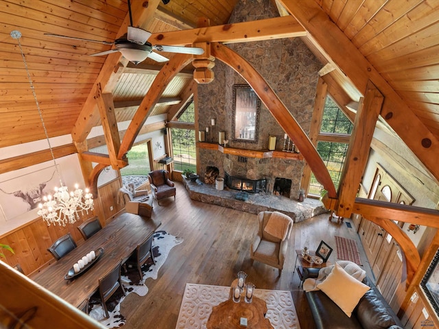 unfurnished living room with a fireplace, hardwood / wood-style flooring, beamed ceiling, wood walls, and wood ceiling