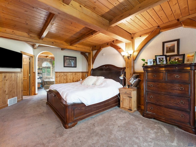 bedroom featuring beamed ceiling, light colored carpet, and wood ceiling