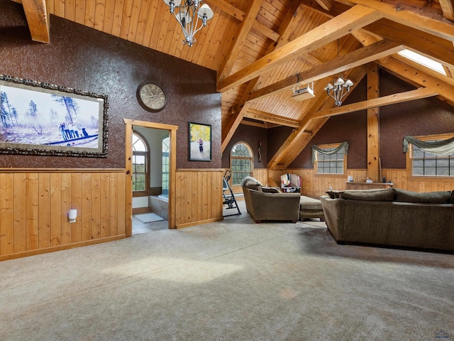 carpeted living room featuring beamed ceiling, wooden walls, high vaulted ceiling, and a chandelier