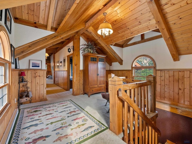 hall featuring lofted ceiling with beams, a chandelier, wood walls, and light colored carpet