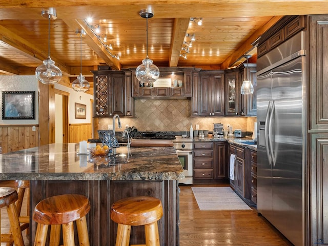 kitchen with premium appliances, wood ceiling, dark hardwood / wood-style floors, beamed ceiling, and a kitchen breakfast bar