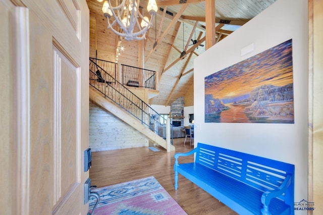 interior space featuring wood-type flooring, high vaulted ceiling, an inviting chandelier, beam ceiling, and wood walls