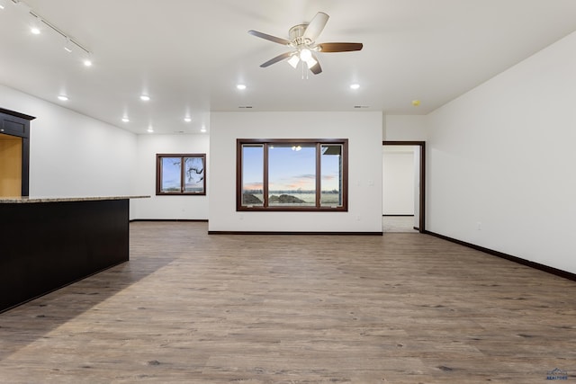 unfurnished living room with ceiling fan, recessed lighting, wood finished floors, and baseboards