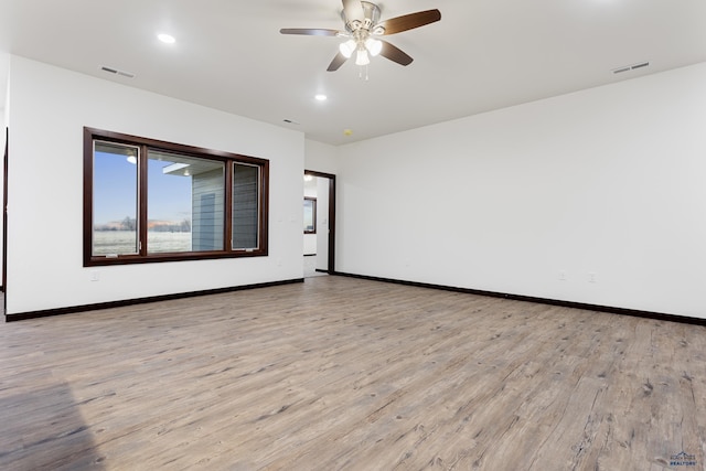 empty room with a ceiling fan, visible vents, light wood-style flooring, and baseboards