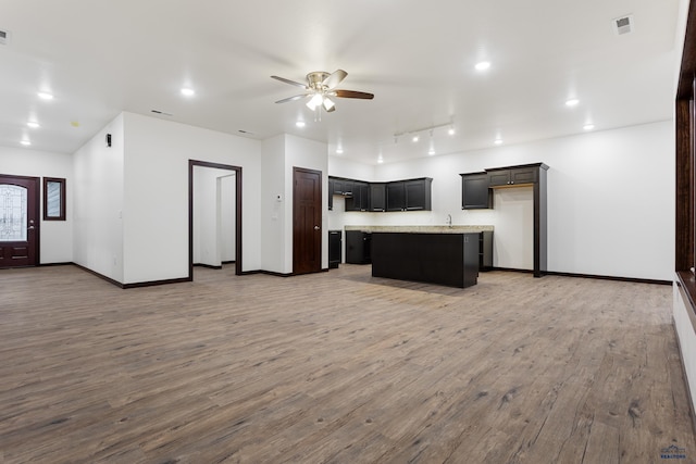 kitchen featuring wood finished floors, a kitchen island, a ceiling fan, open floor plan, and light countertops