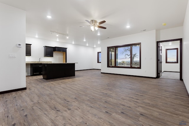 kitchen with baseboards, a kitchen island, open floor plan, dark wood-type flooring, and light countertops