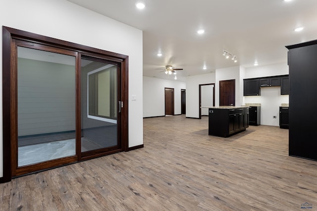 kitchen featuring a ceiling fan, a kitchen island, open floor plan, light countertops, and light wood-style floors