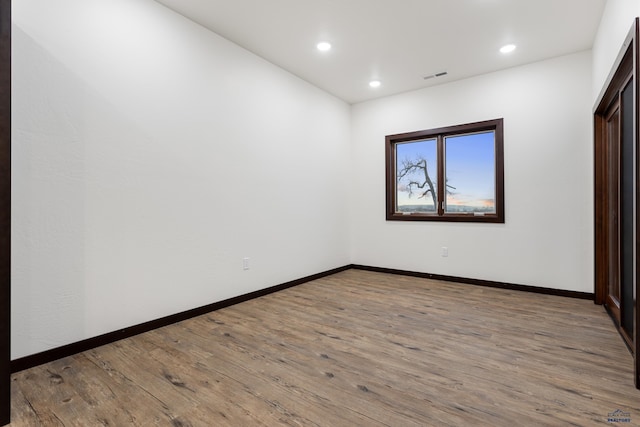 spare room featuring baseboards, visible vents, wood finished floors, and recessed lighting