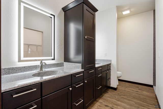 bathroom with baseboards, vanity, toilet, and wood finished floors