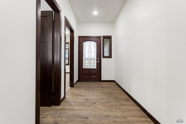 doorway to outside featuring baseboards and wood finished floors