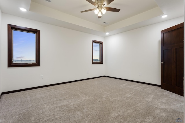 unfurnished room with recessed lighting, a raised ceiling, light colored carpet, and baseboards